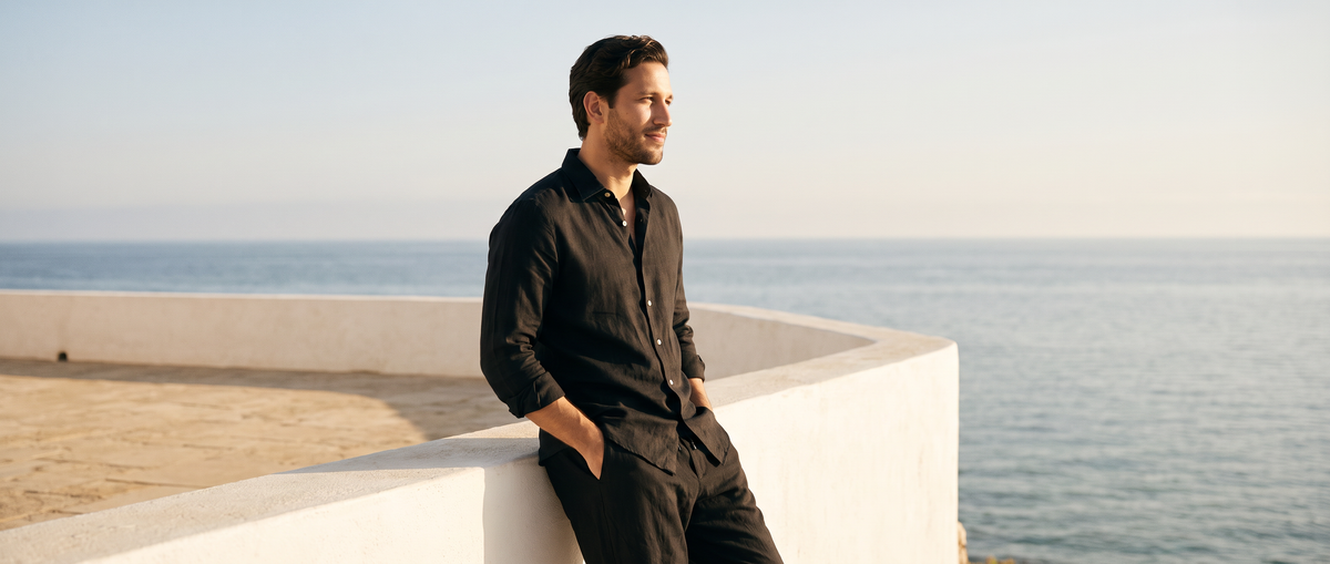 Man in a black linen-look shirt on a seaside terrace
