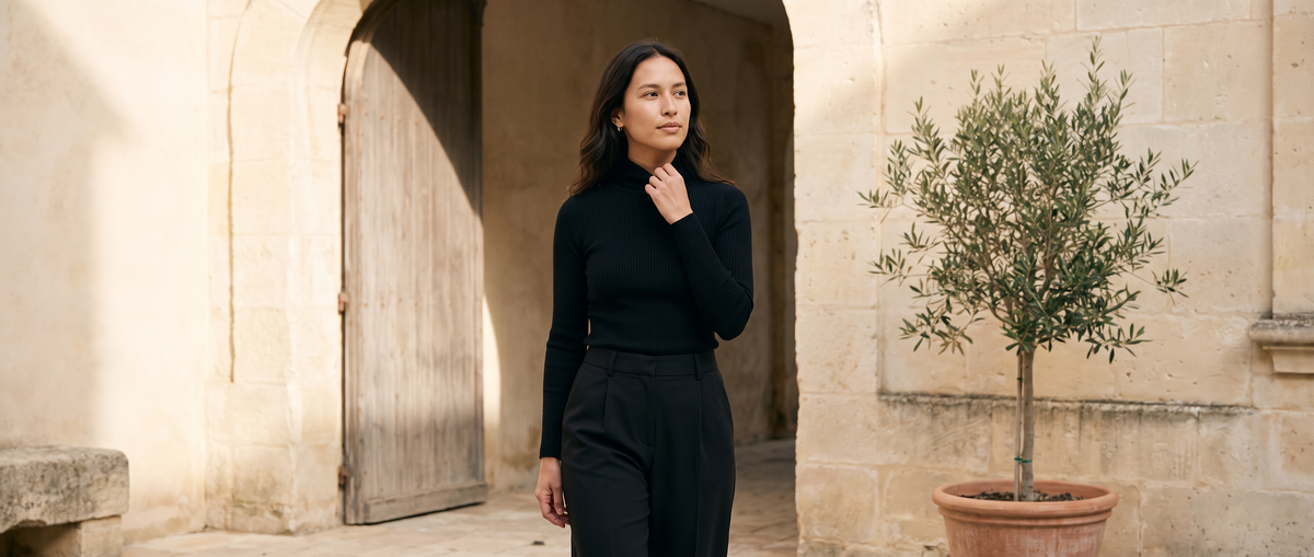 Woman in a black rib-knit top and wide-leg trousers in a stone courtyard